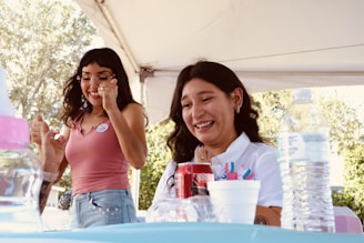 Two young women laughing at a table