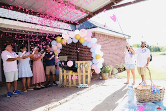 Family celebrating a gender reveal with pink confetti.