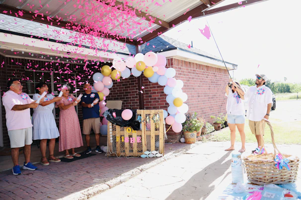 Family celebrating a gender reveal with pink confetti.