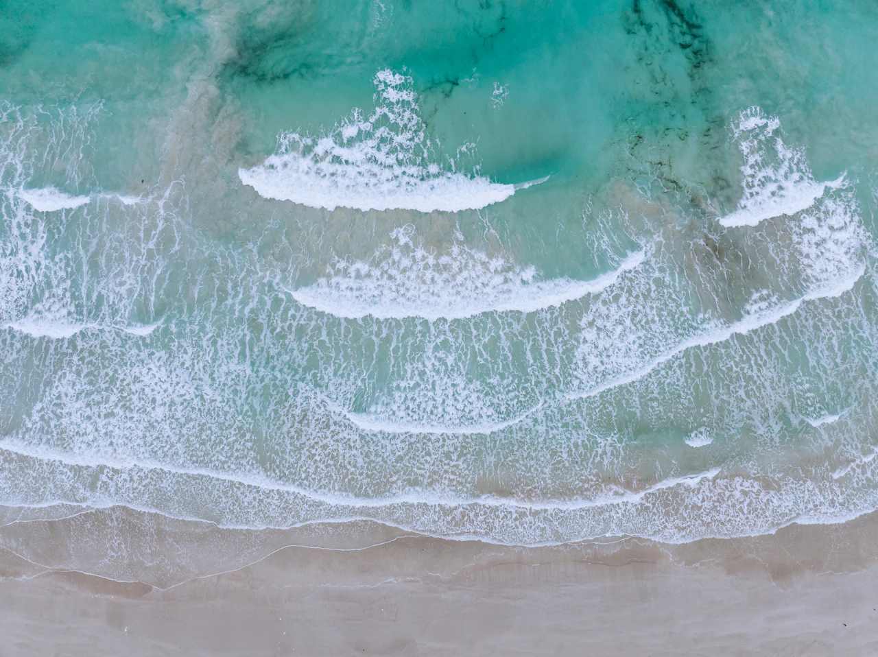 Aerial view of ocean waves crashing on a sandy beach