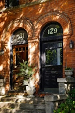 Two brick row house doors with numbers 31 and 129.