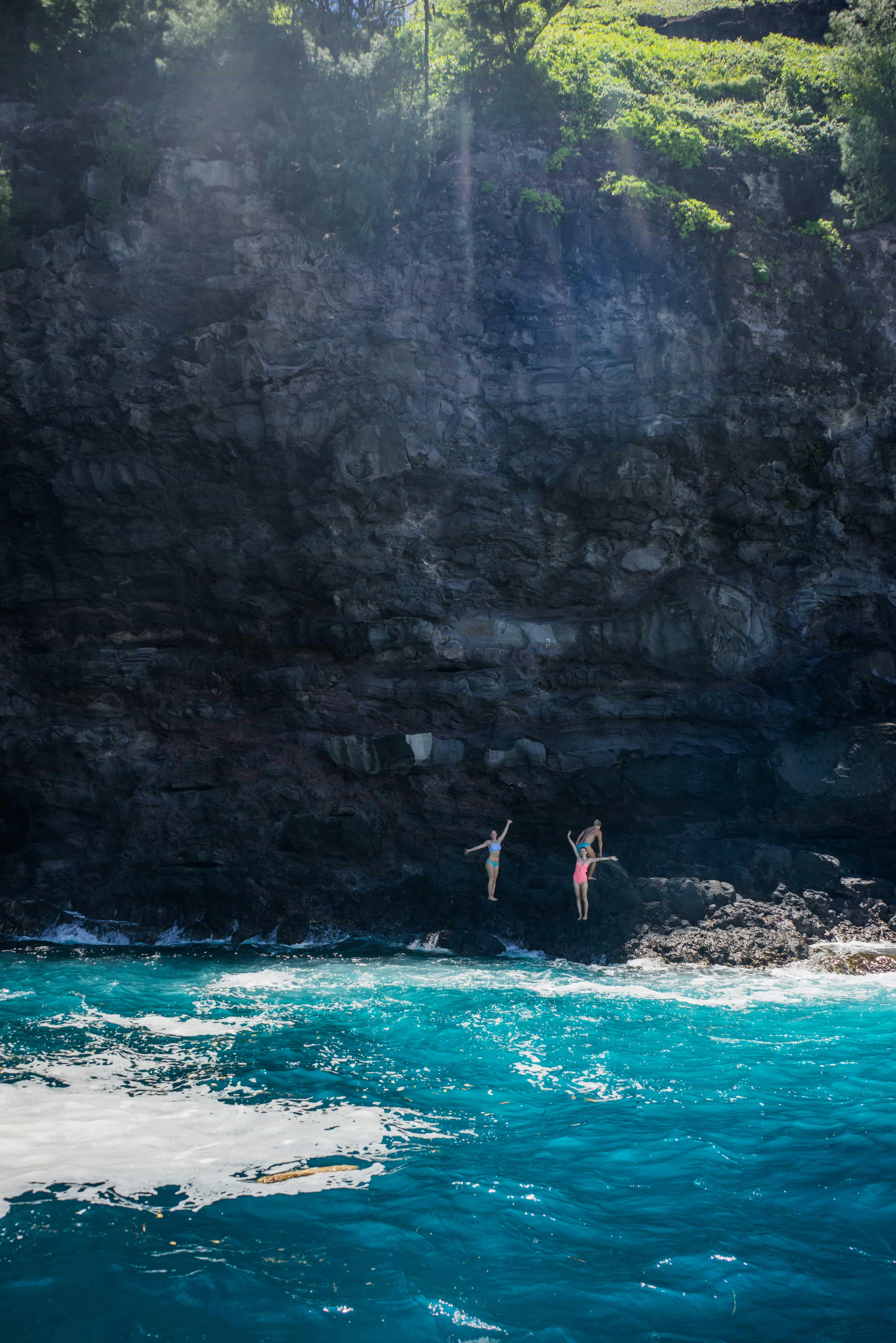 People jumping off a rocky cliff into the ocean photo – Free Summer ...