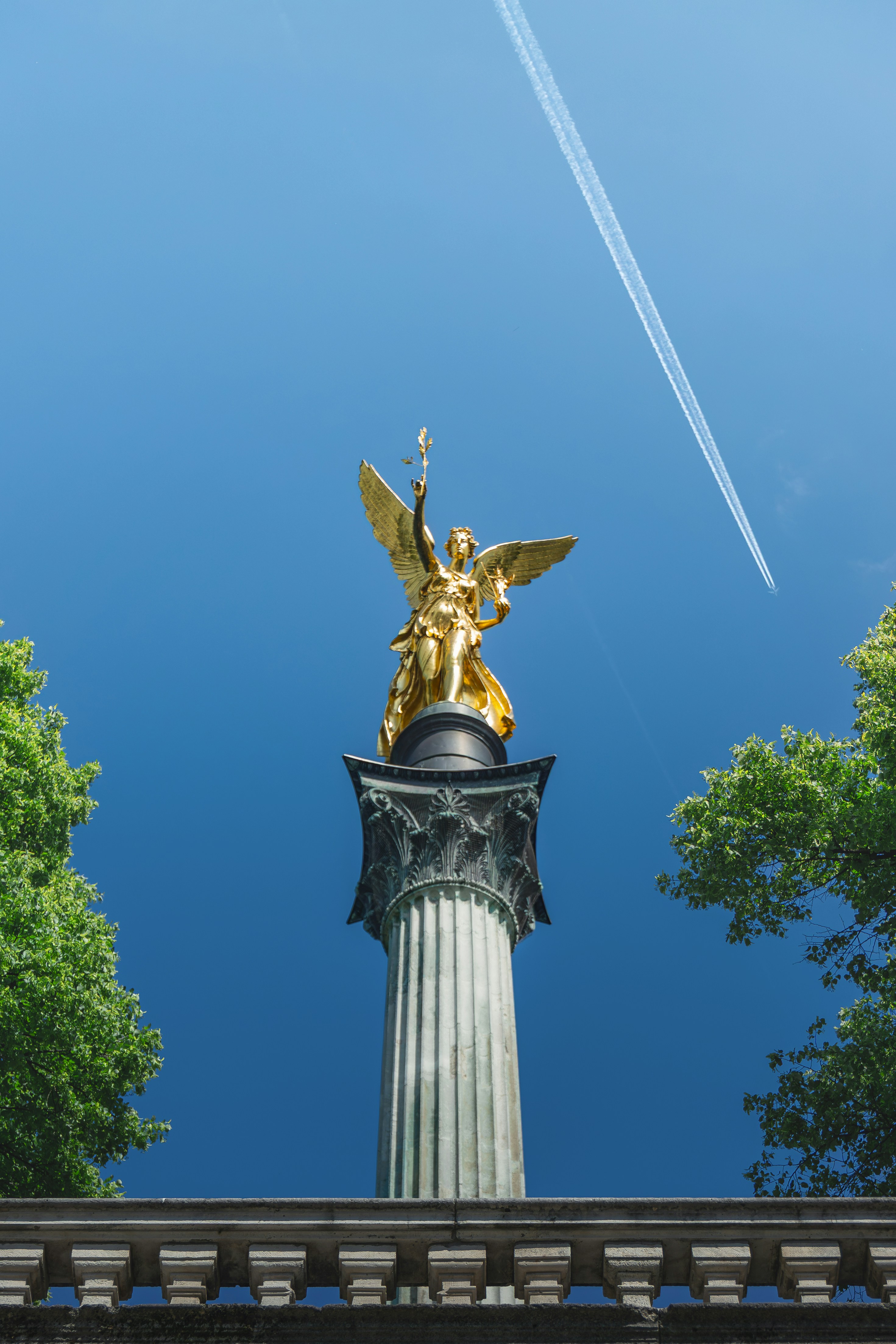 Golden angel statue atop column under blue sky