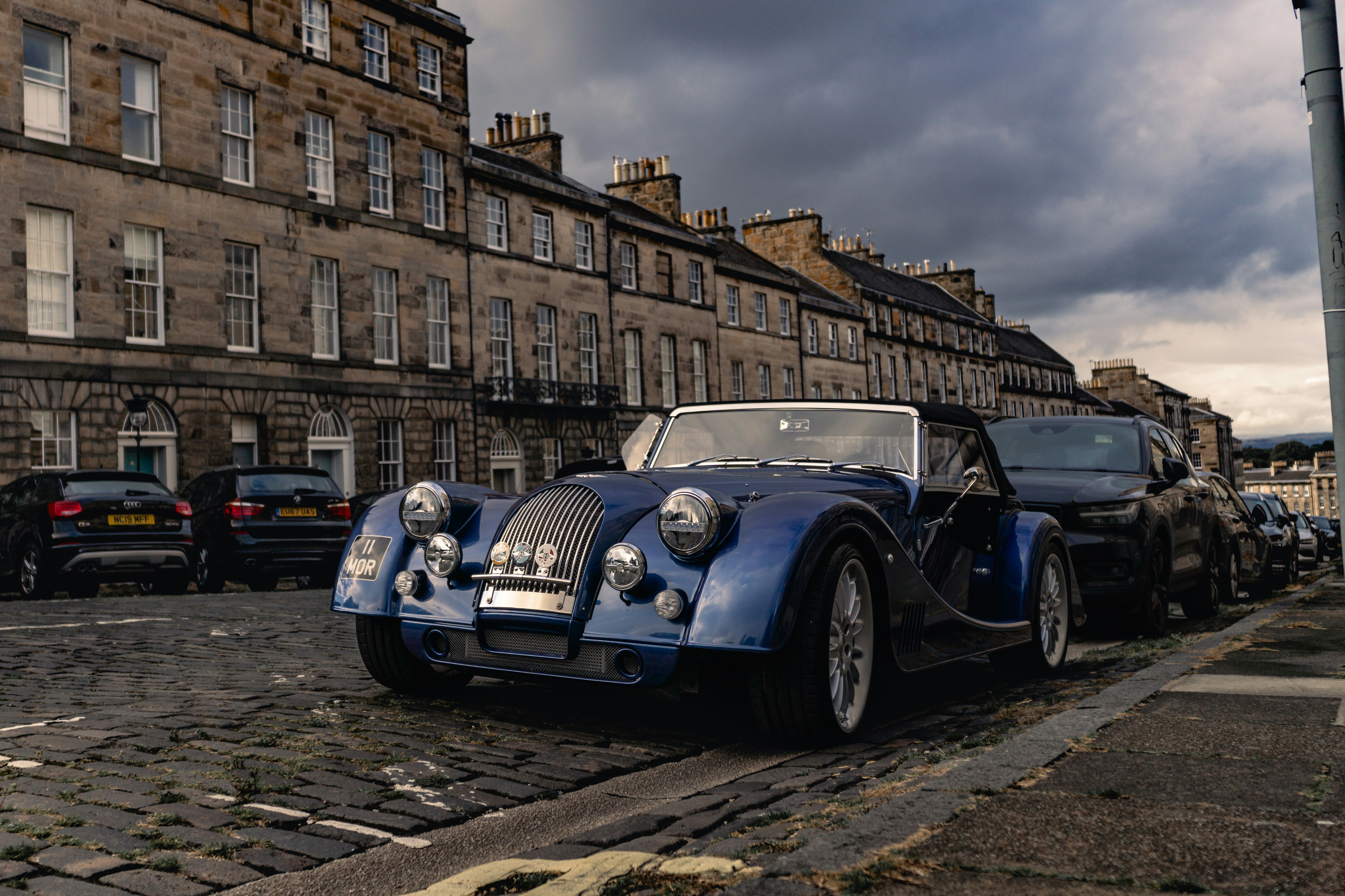 Blue classic car parked on cobblestone street
