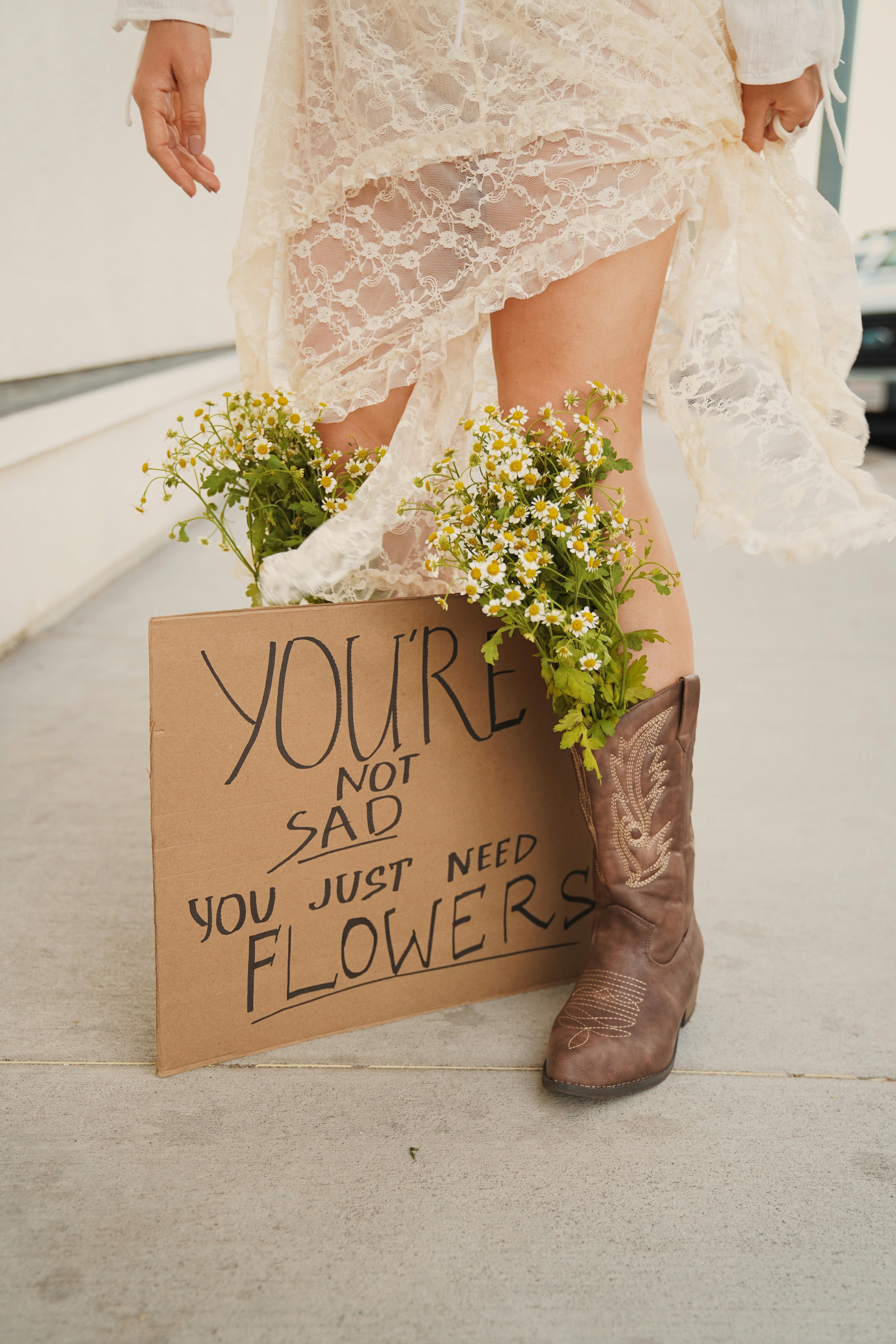 Woman in cowboy boots with flowers and sign
