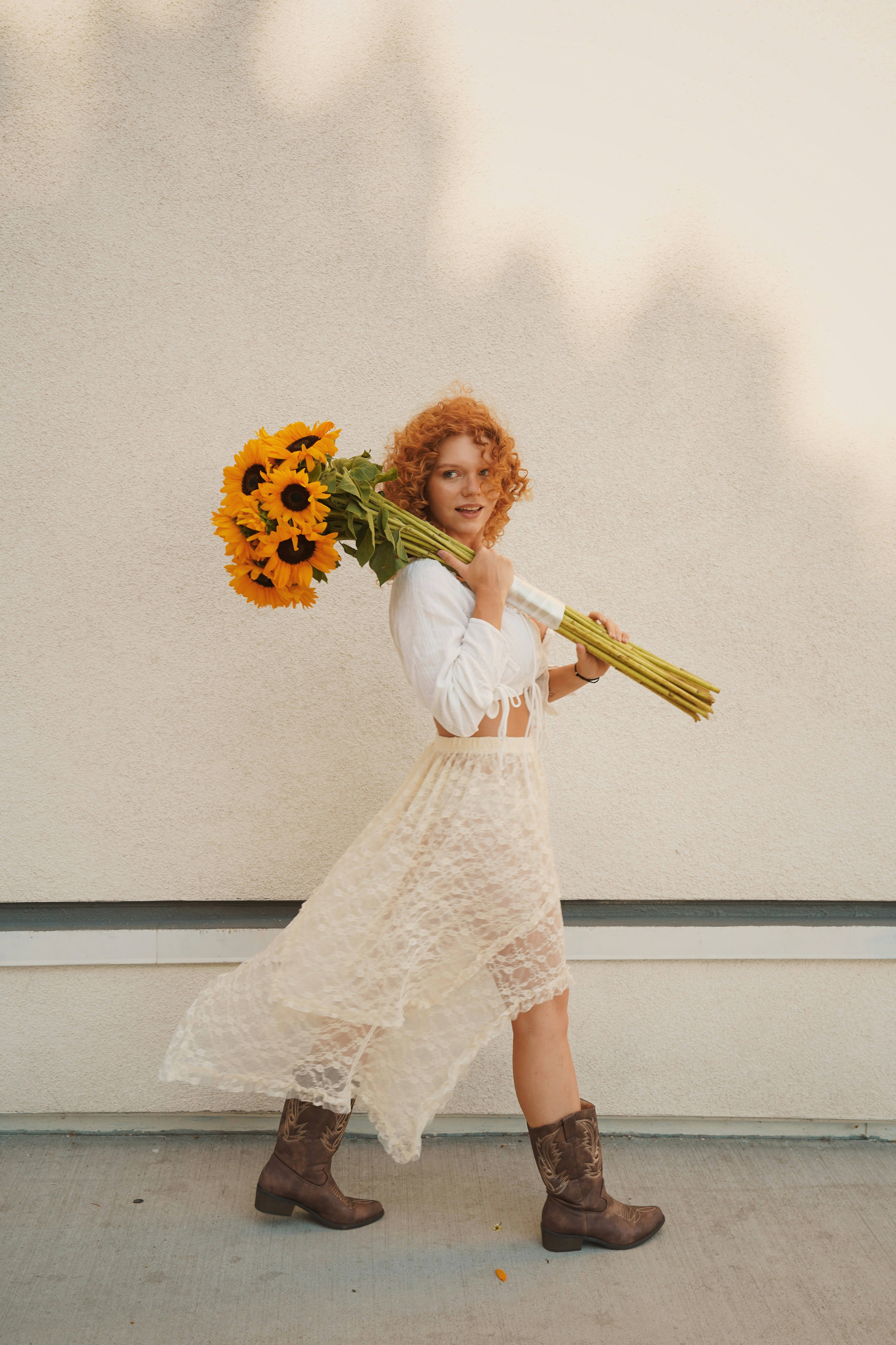 Woman with red curly hair carrying sunflowers