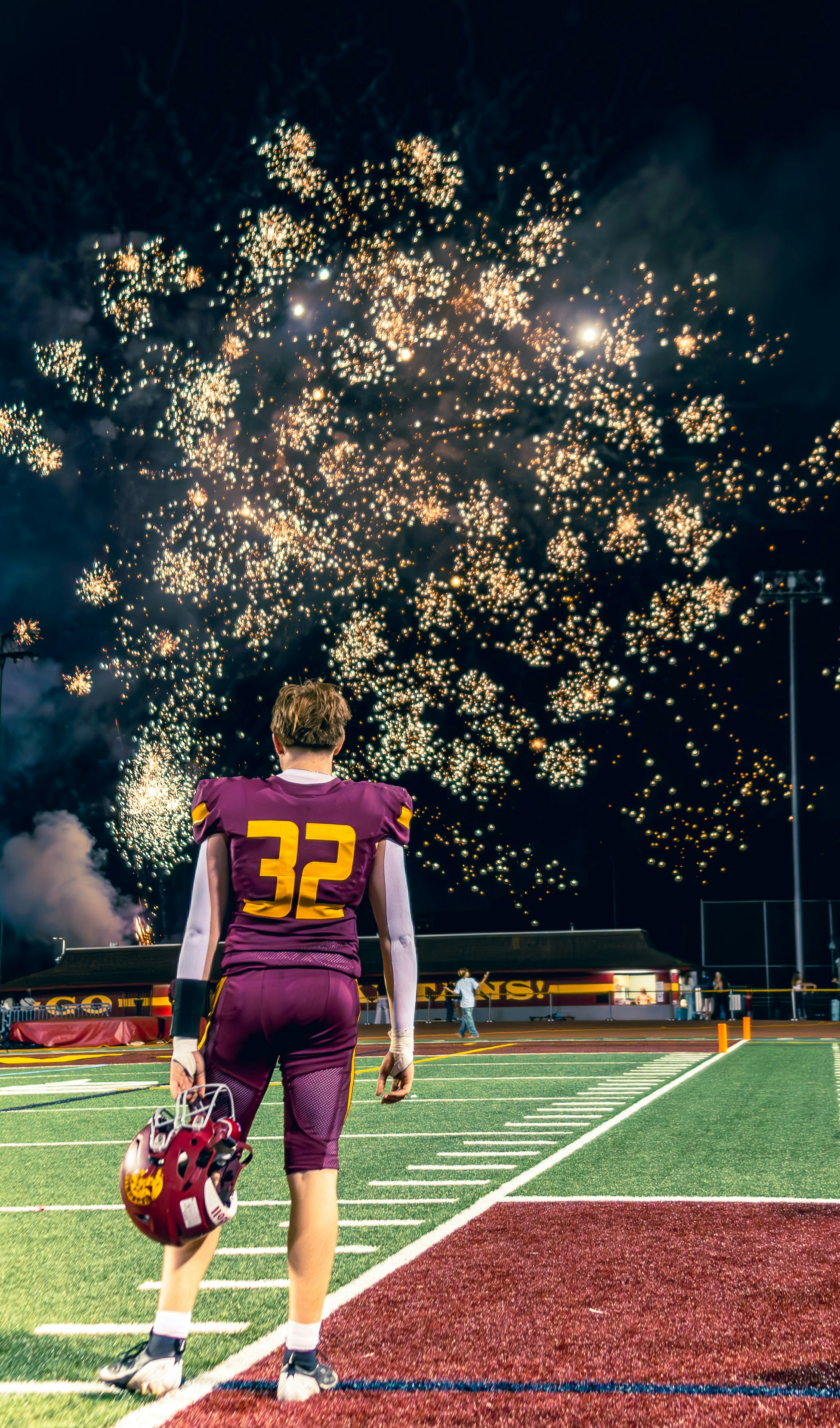 Jugador de fútbol observa fuegos artificiales en el campo.