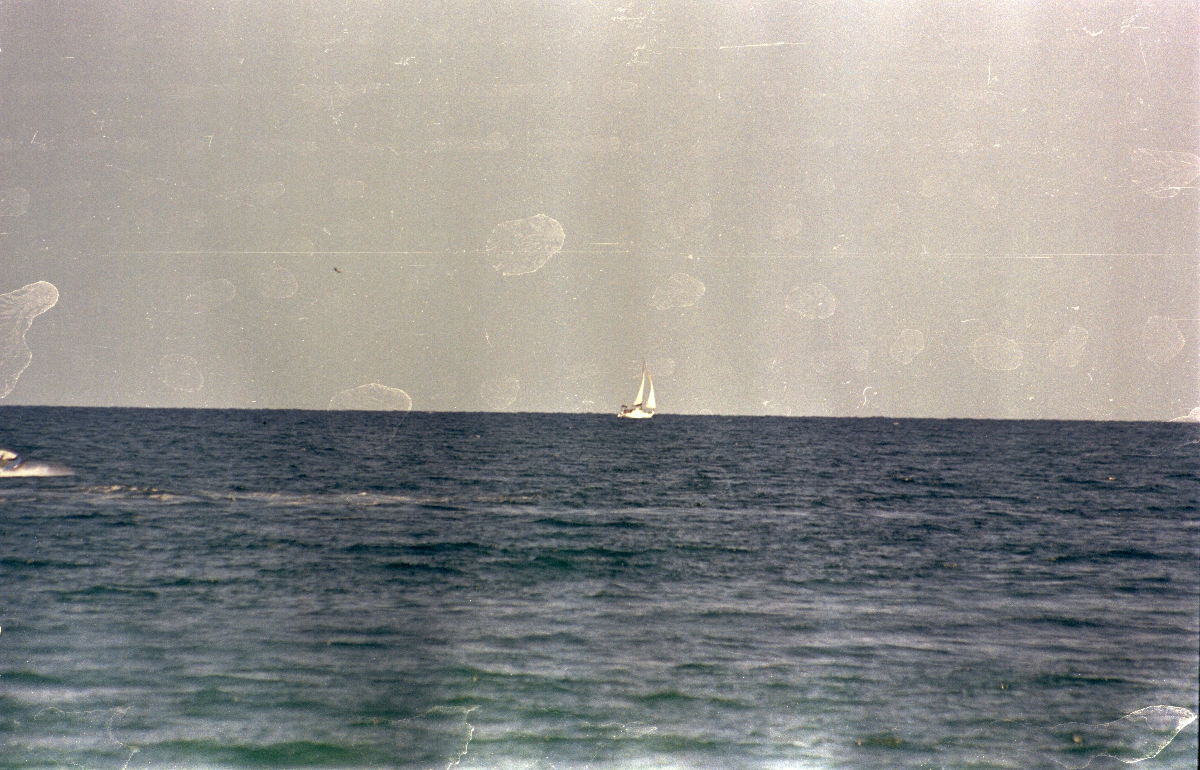 A lone sailboat on the vast ocean horizon