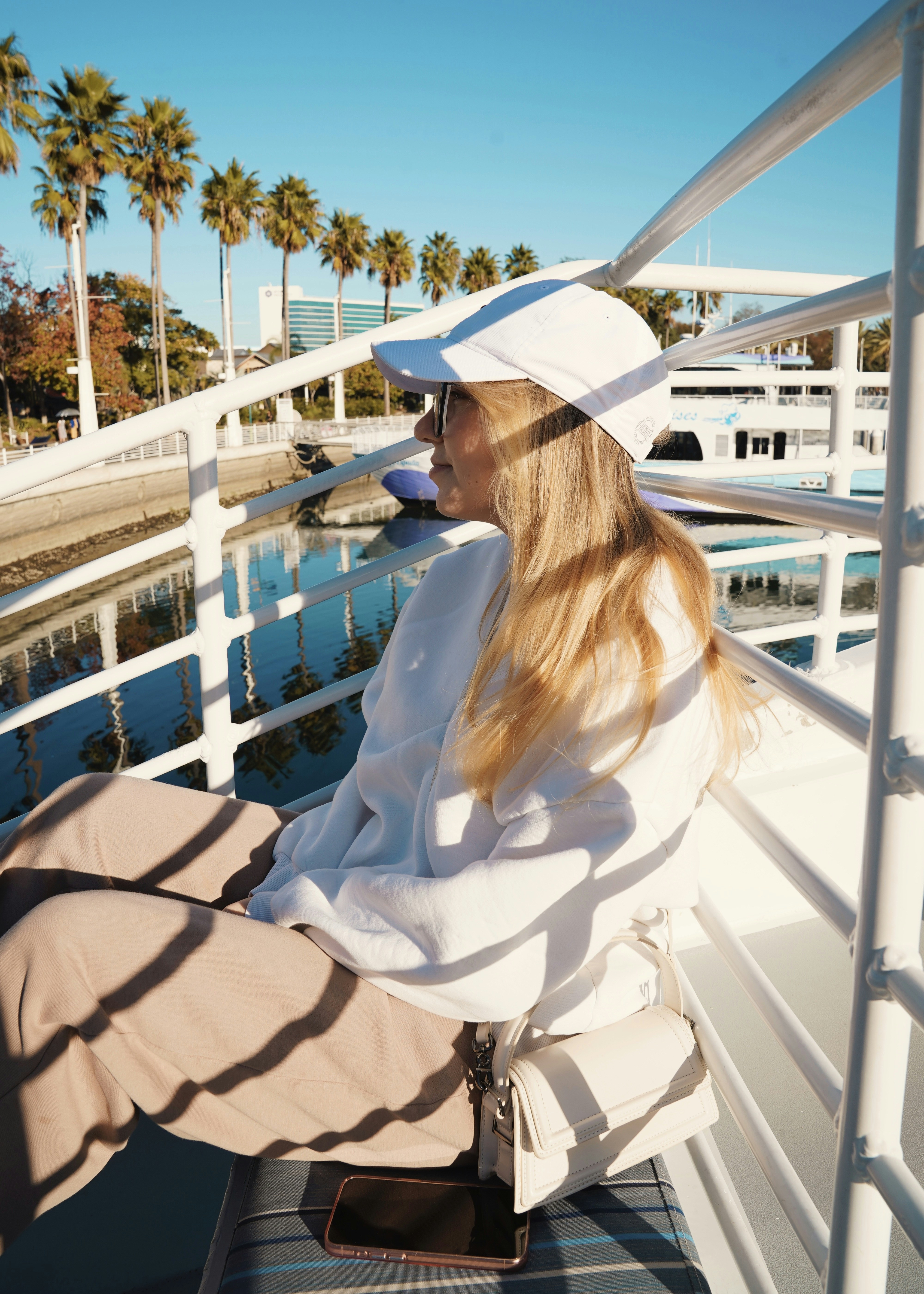 Frau mit weißem Hut auf Boot mit Palmen.