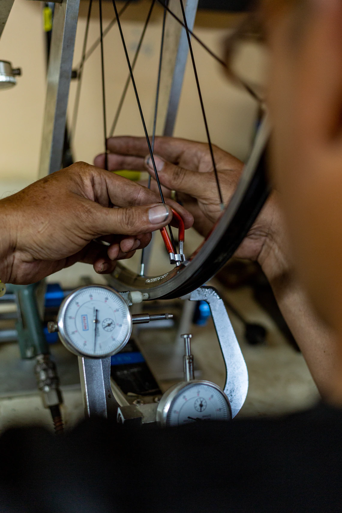 Bicycle mechanic carefully adjusting wheel spokes with tools