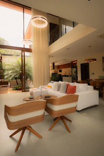 Modern living room with white sofa and wooden chairs.