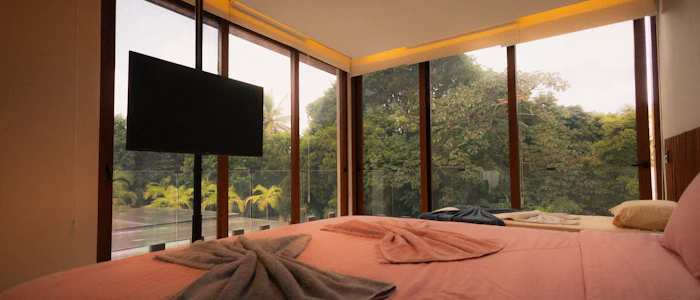 A bedroom with floor-to-ceiling glass looking into the forest
