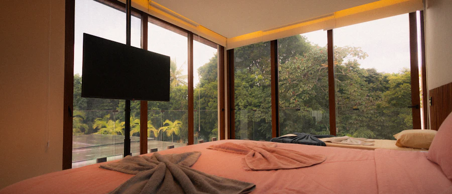 A bedroom with floor-to-ceiling glass looking into the forest