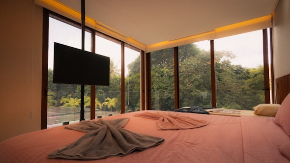 Bedroom with large windows overlooking lush green forest