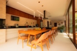 Modern kitchen and dining area with long orange table.