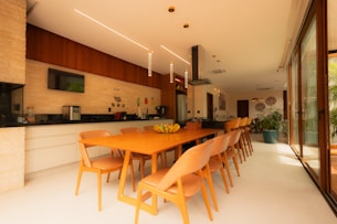 Modern kitchen and dining area with long orange table.