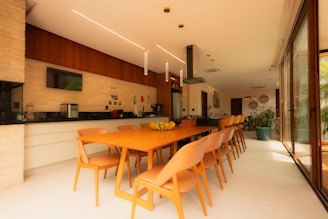 Modern kitchen and dining area with long orange table.