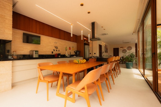 Modern kitchen and dining area with long orange table.