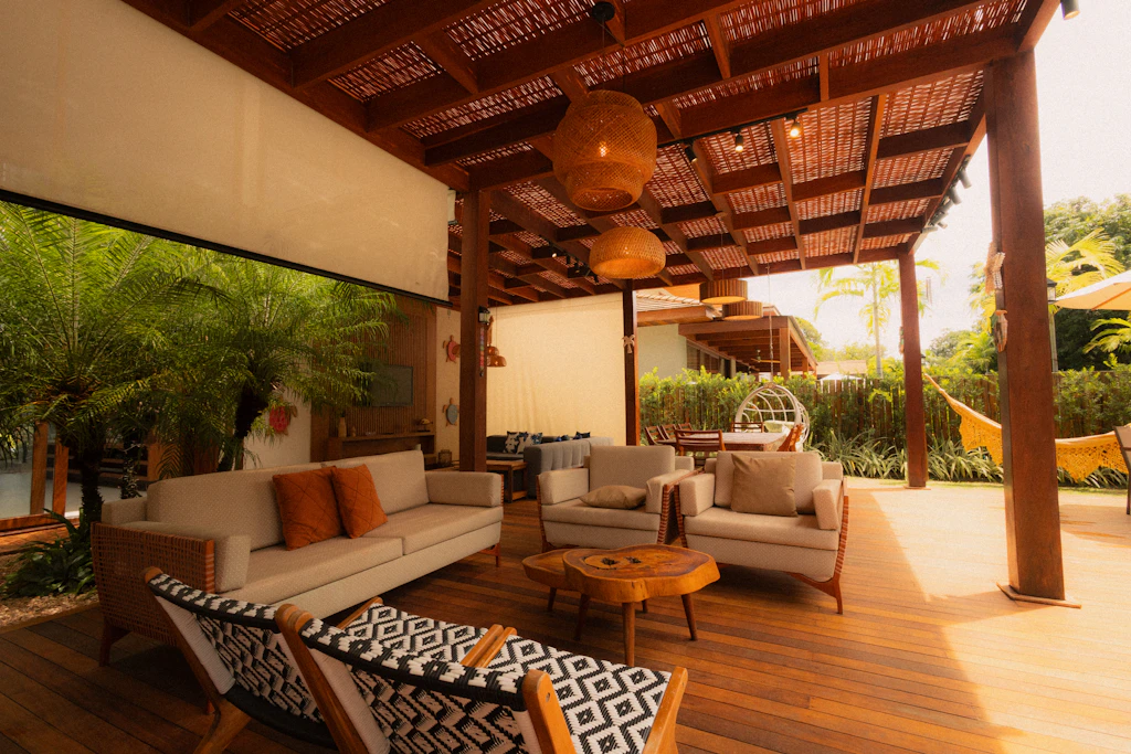Open-air living room with hanging chairs under a timber roof