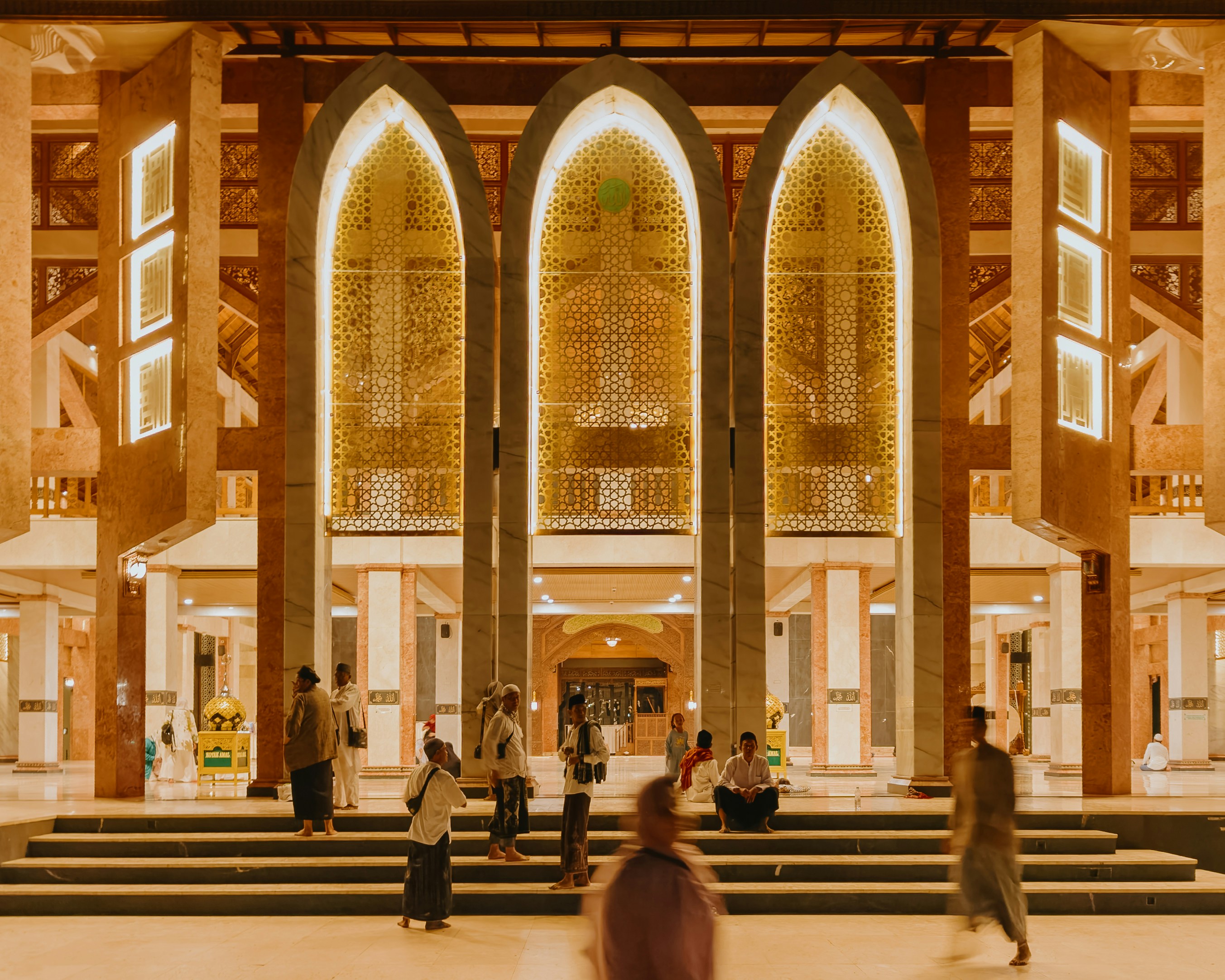 People gathered outside a mosque with ornate arched entrances