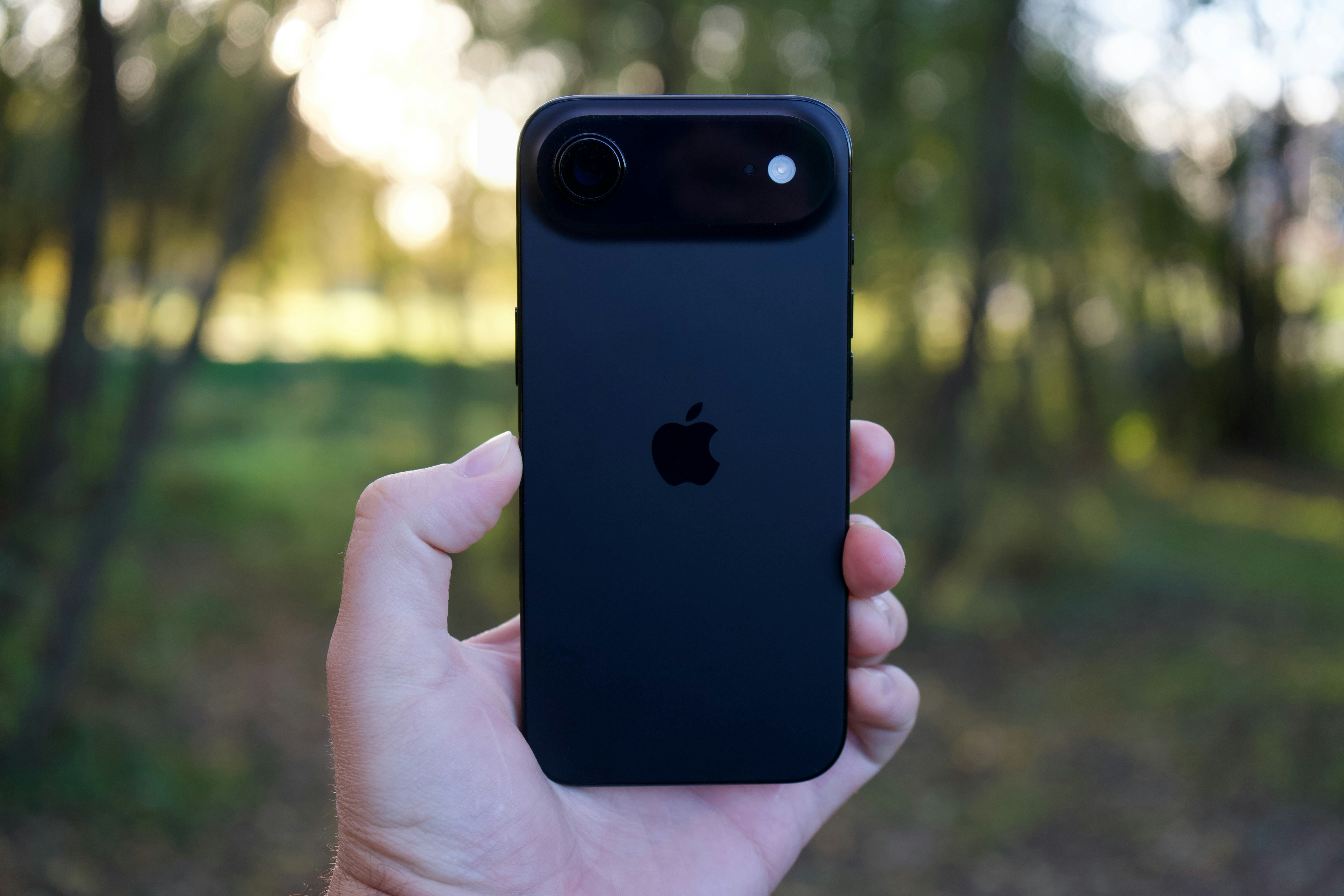 Mano sosteniendo un smartphone negro con el logo de Apple.