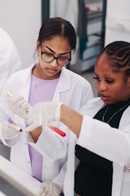 Two young women in lab coats examining blood samples.