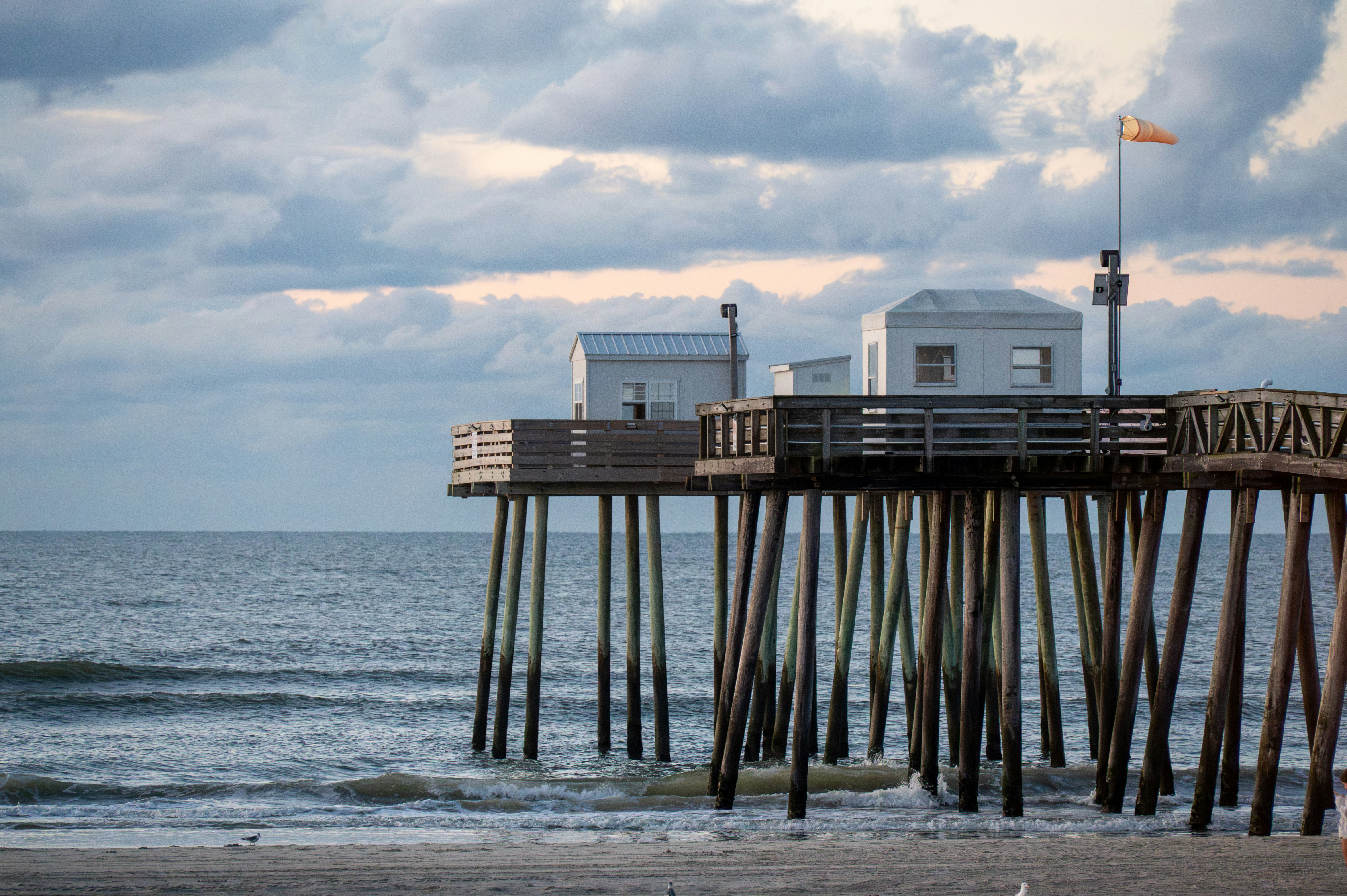 Wooden pier with small buildings over the ocean.