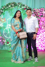 Couple posing in front of a floral backdrop