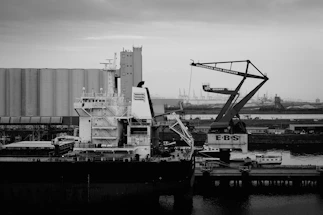 Cargo ship docked at industrial port with cranes