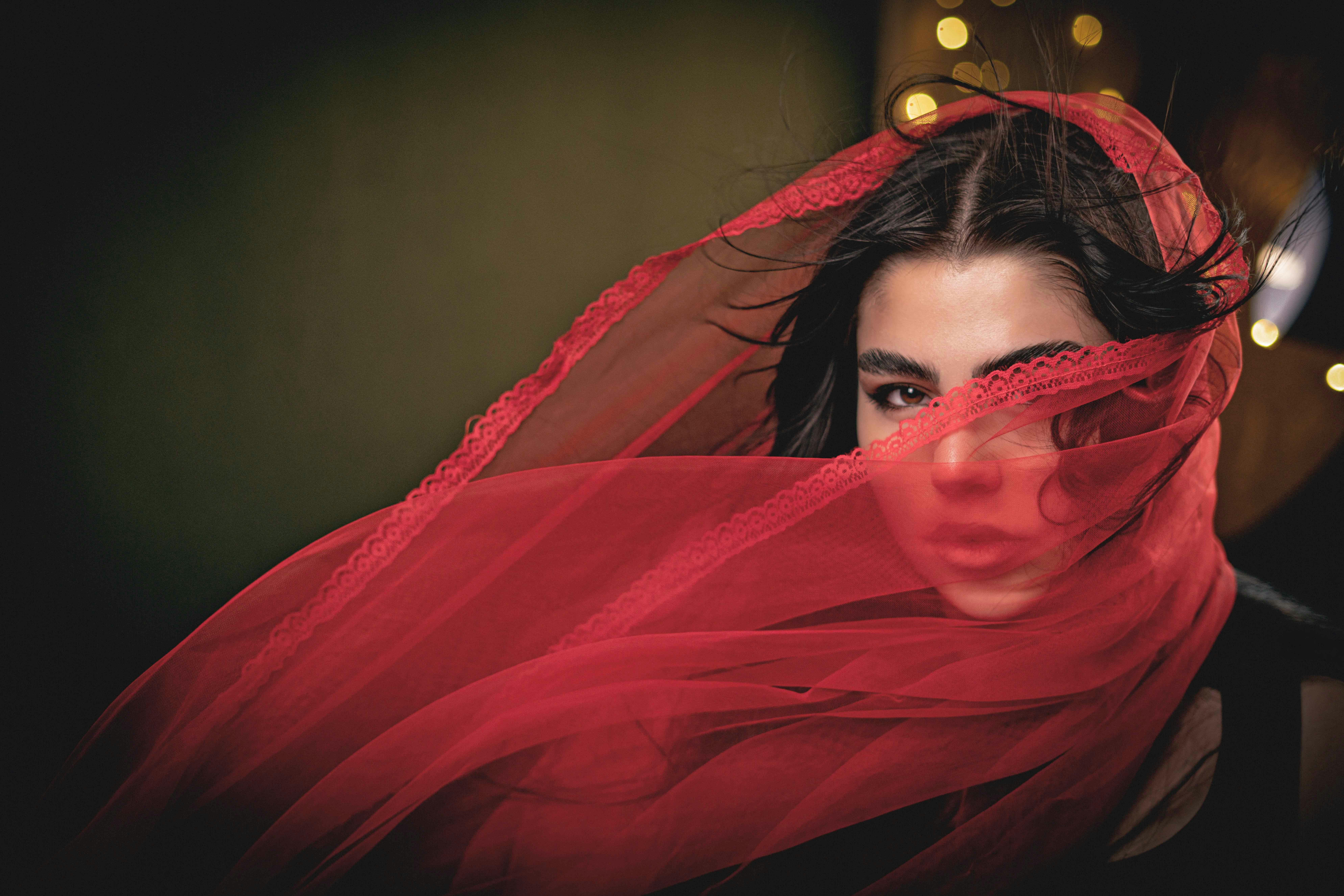 Woman with a red veil obscuring her face.