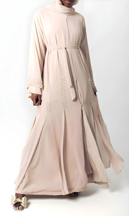 Woman in elegant beige abaya with intricate embroidery.