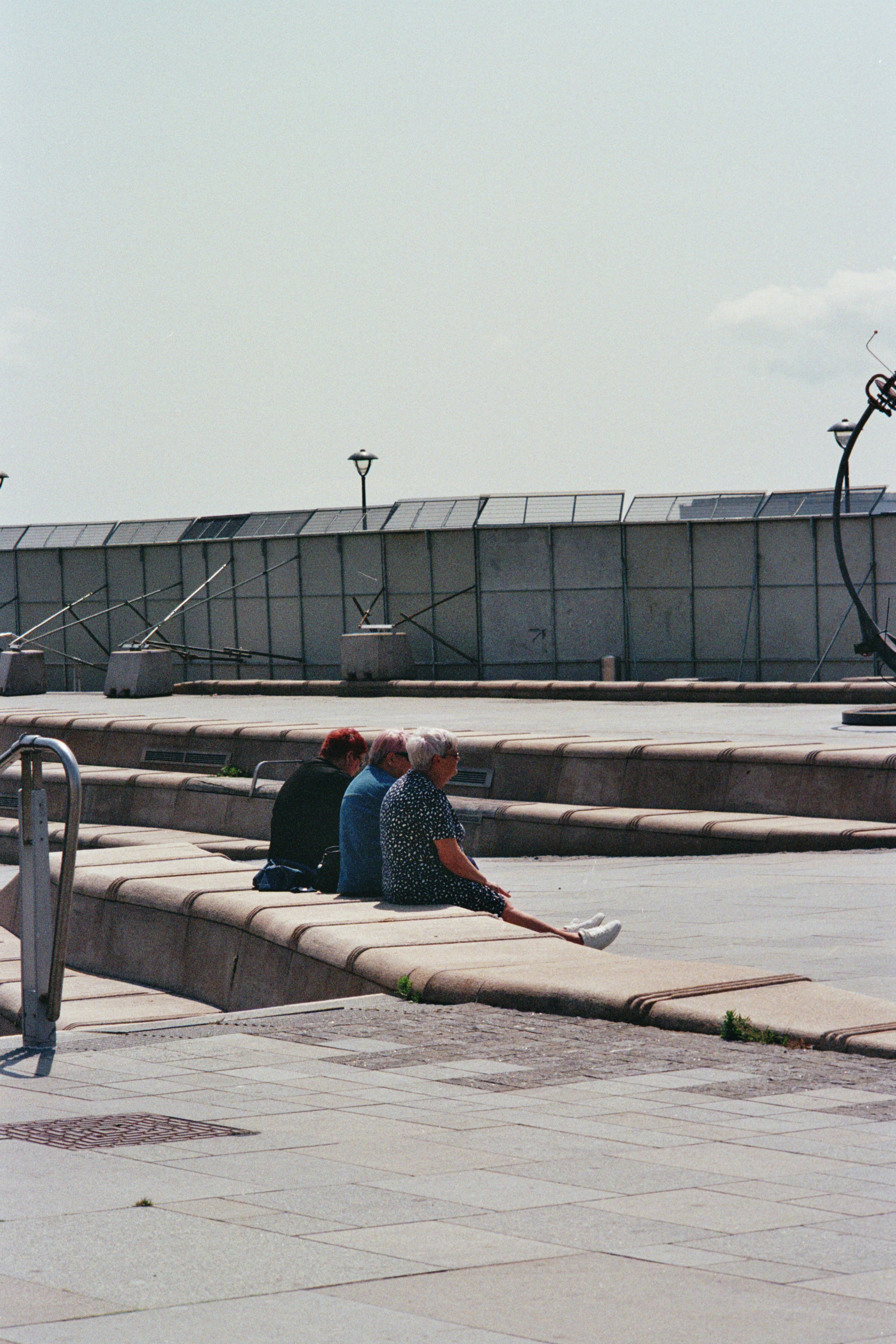 Trois personnes sont assises sur des marches en béton à l’extérieur.
