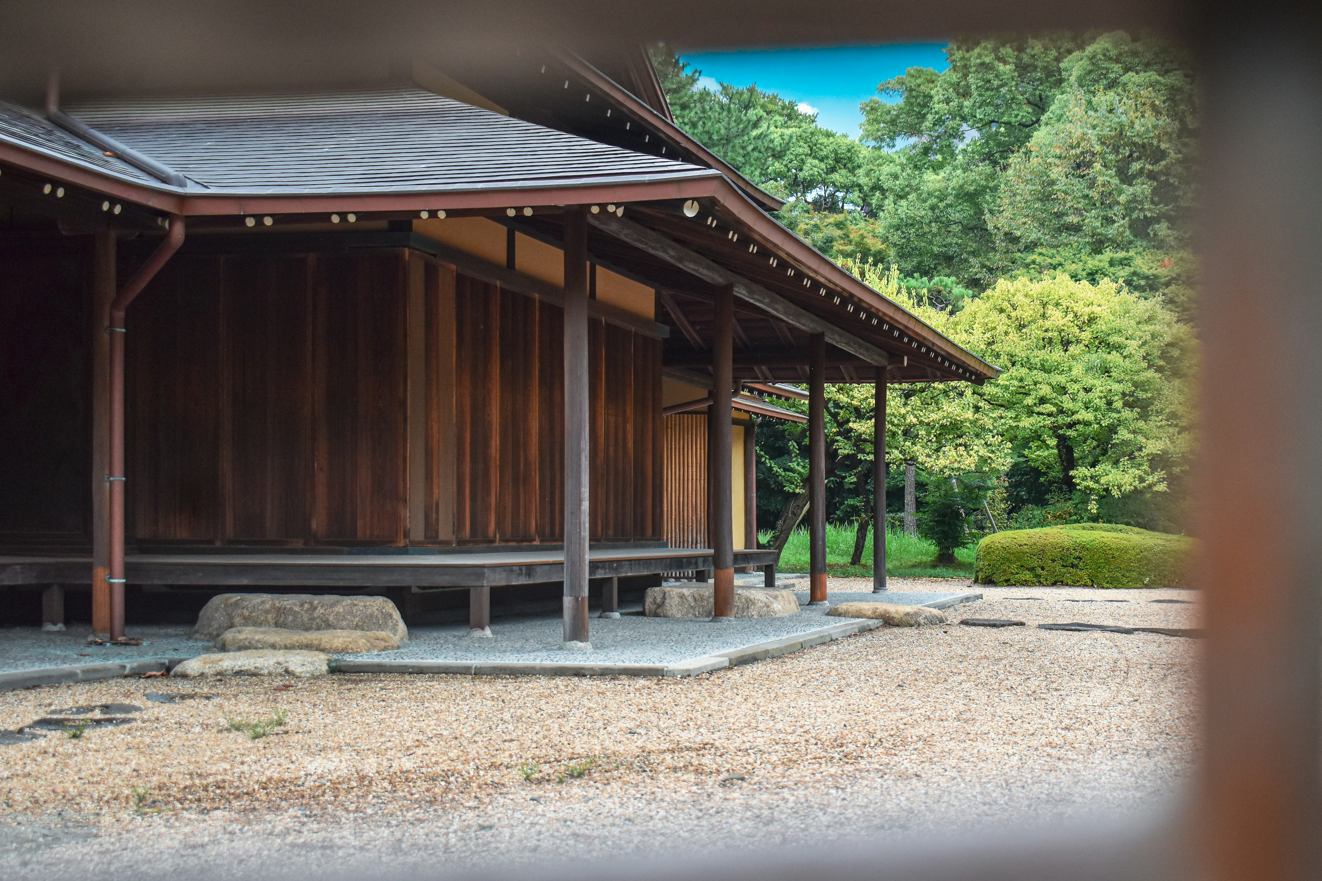 Traditional japanese wooden building with lush green trees.