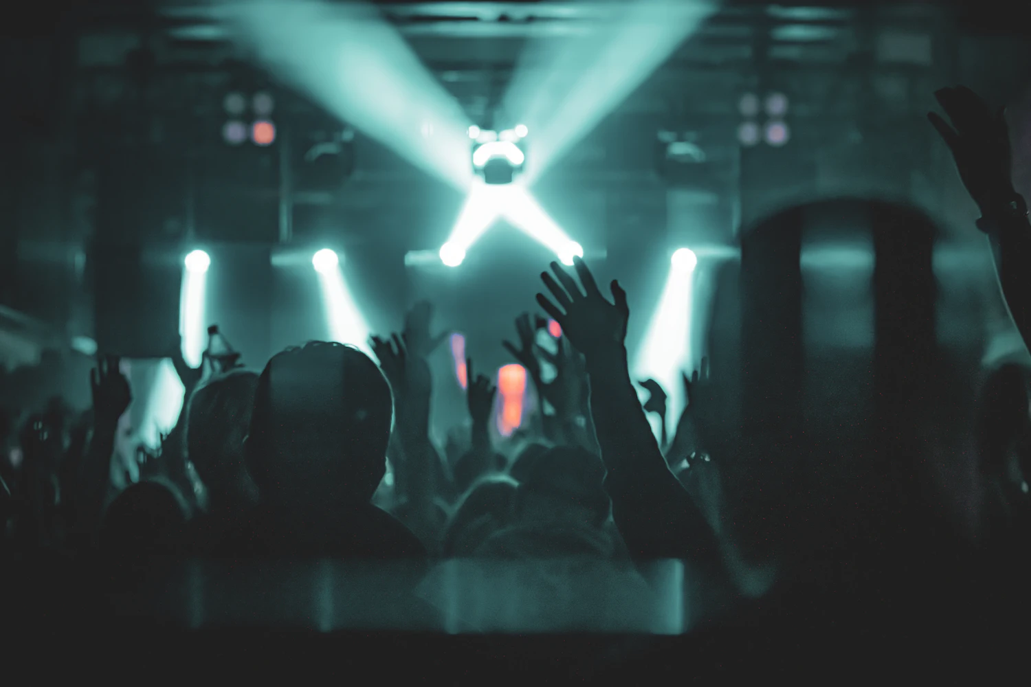Concert crowd with hands raised under stage lights