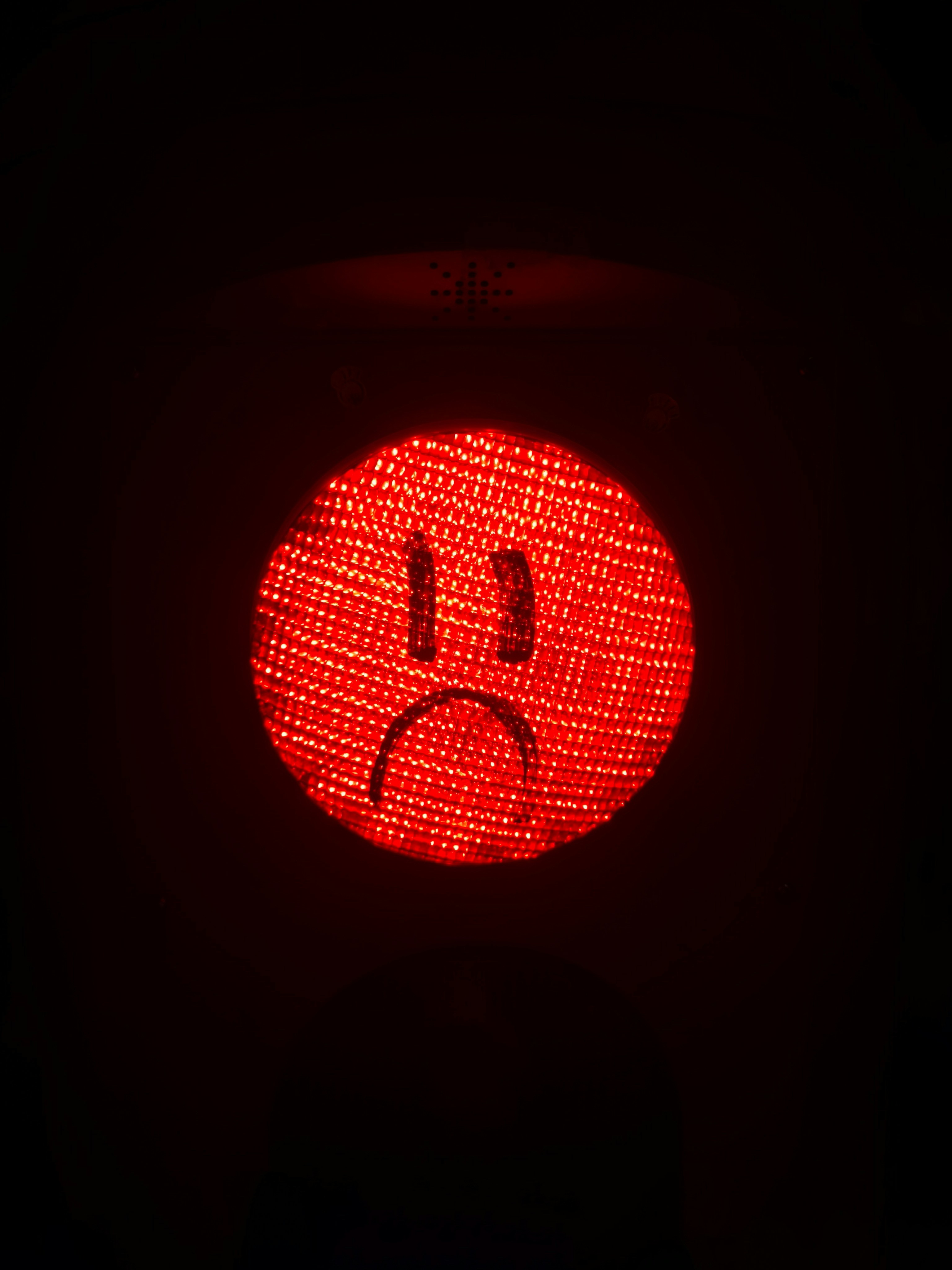 A red light with a sad face drawn on it.