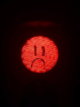 A red light with a sad face drawn on it.