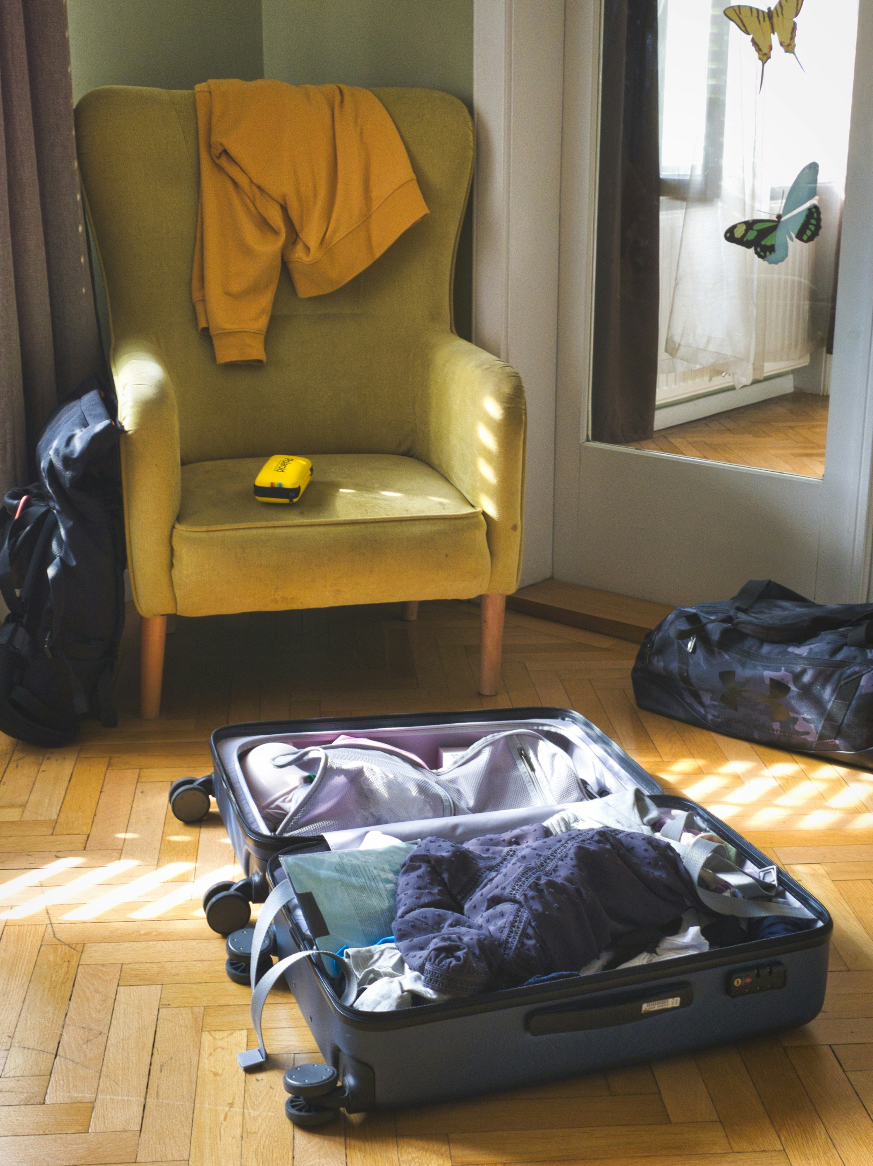 Open suitcase with clothes and armchair in a room