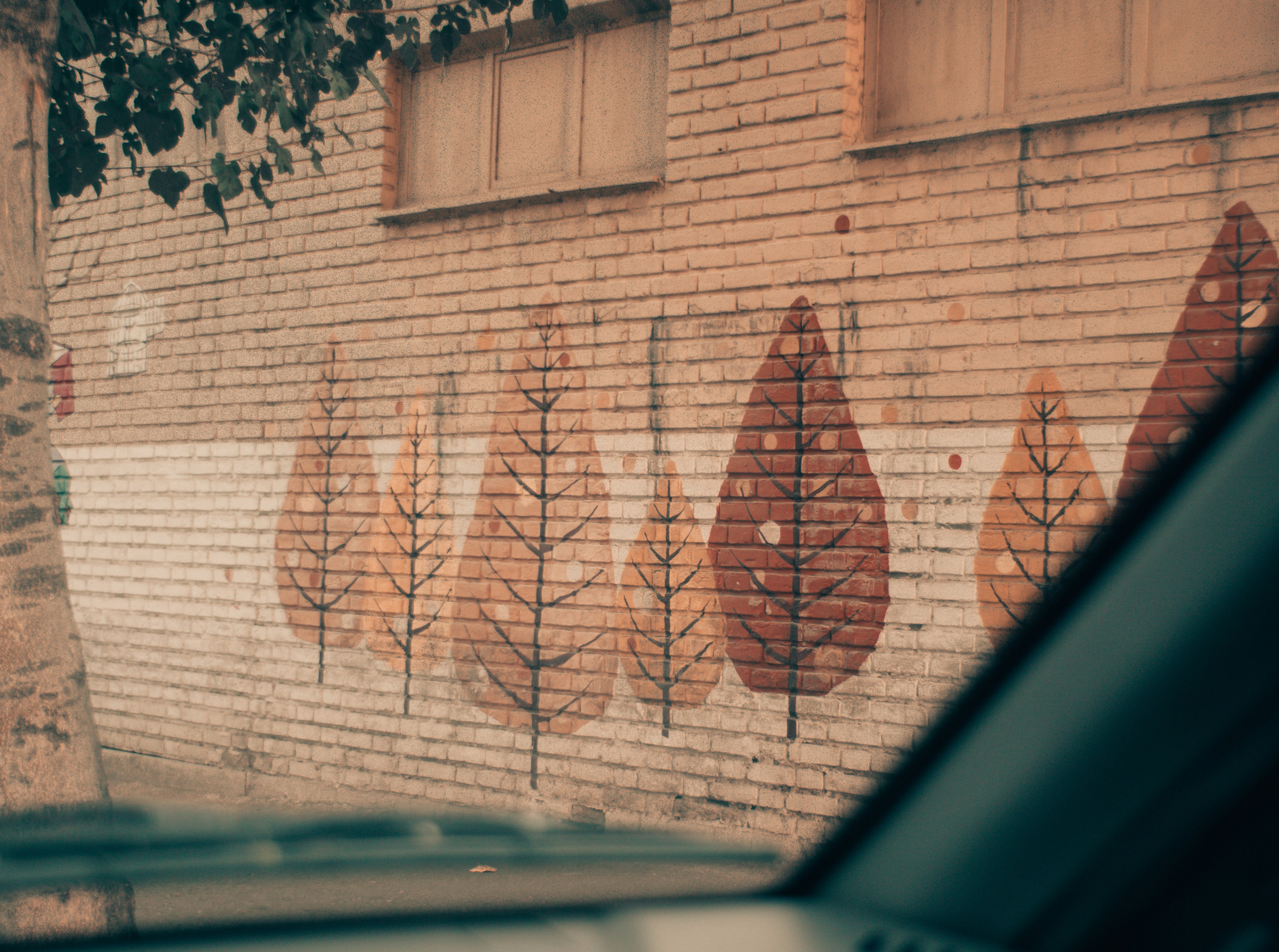Arte murale con foglie stilizzate su edificio in mattoni.