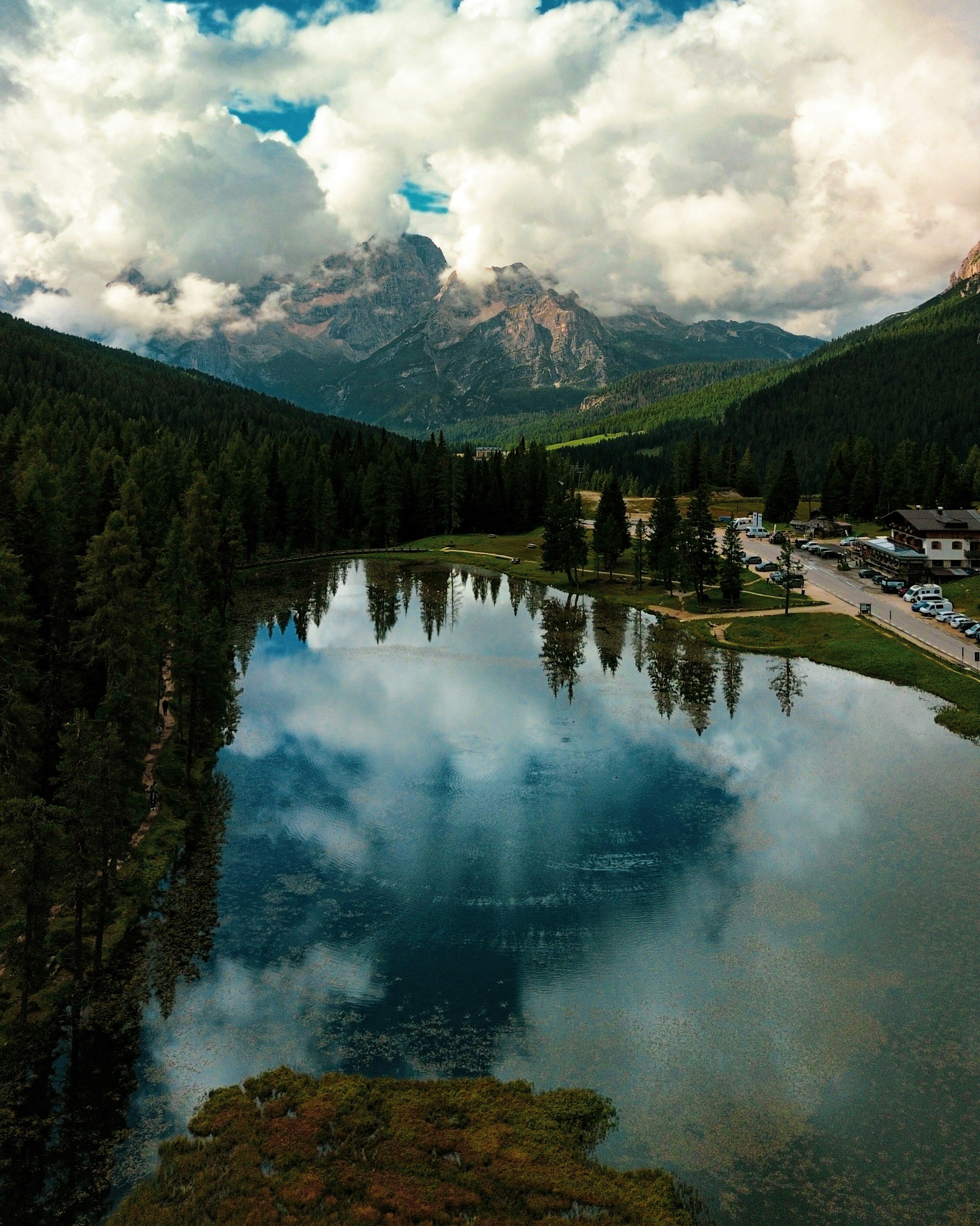 Lago de montaña que refleja el cielo nublado y el bosque circundante
