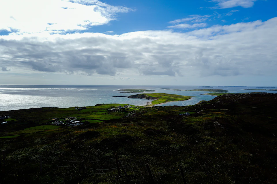Serene coastal landscape features small island surrounded by water and grassy area with trees