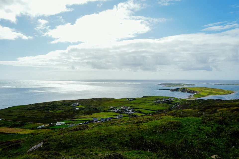 Serene coastal landscape features small island with lush green fields and scattered houses