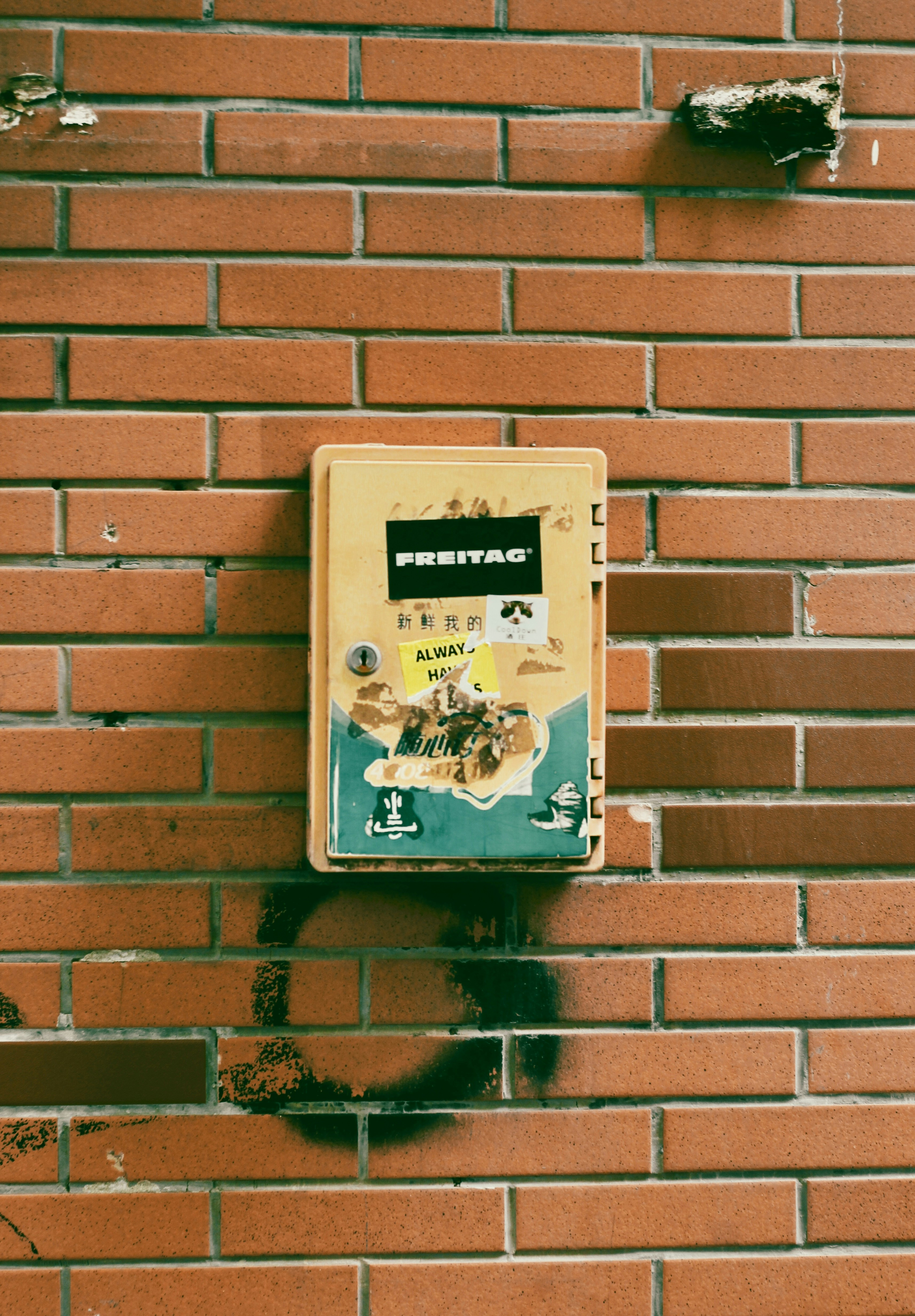 Yellow box with stickers on brick wall