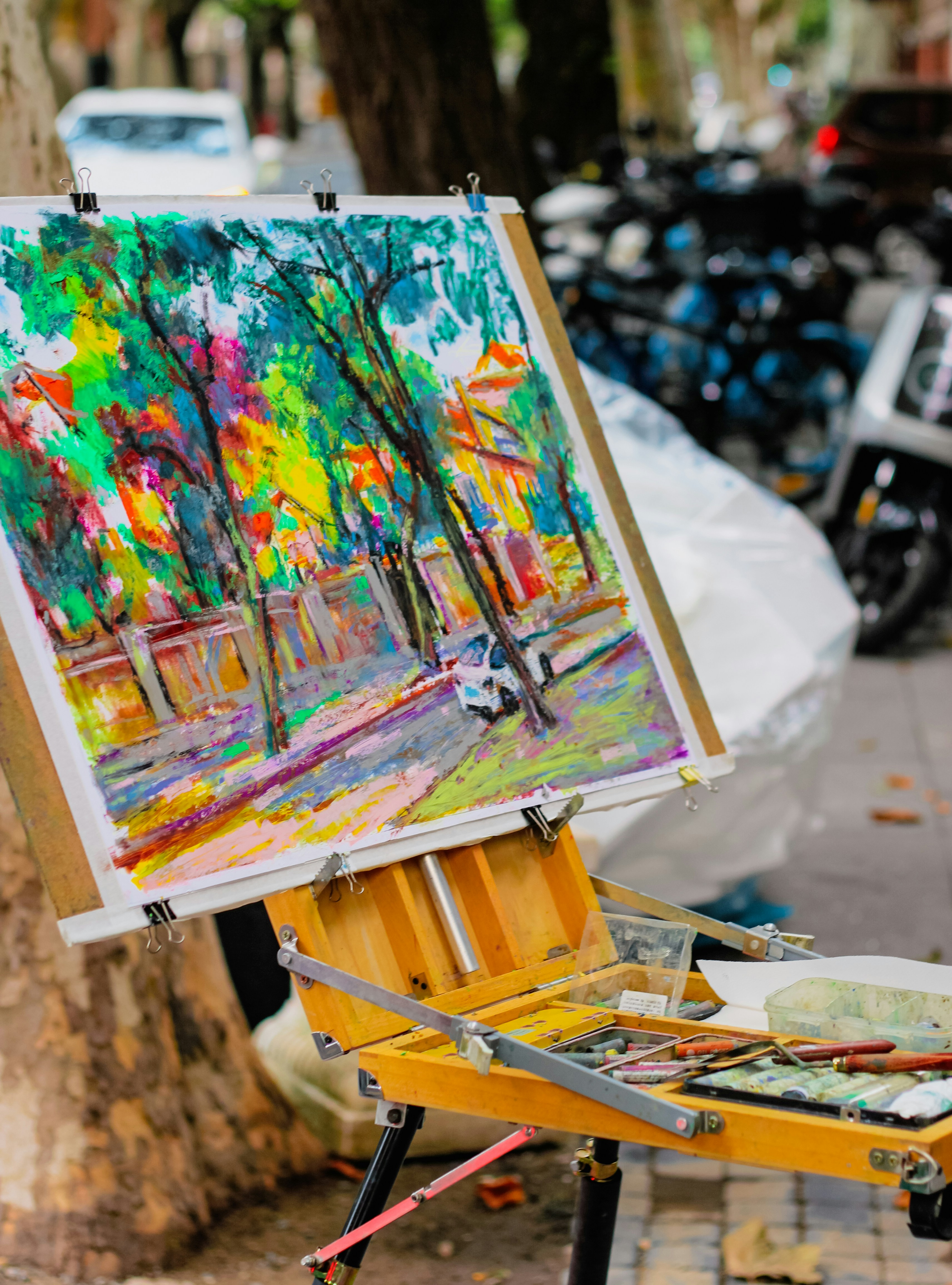 Artist's easel with colorful park landscape painting.
