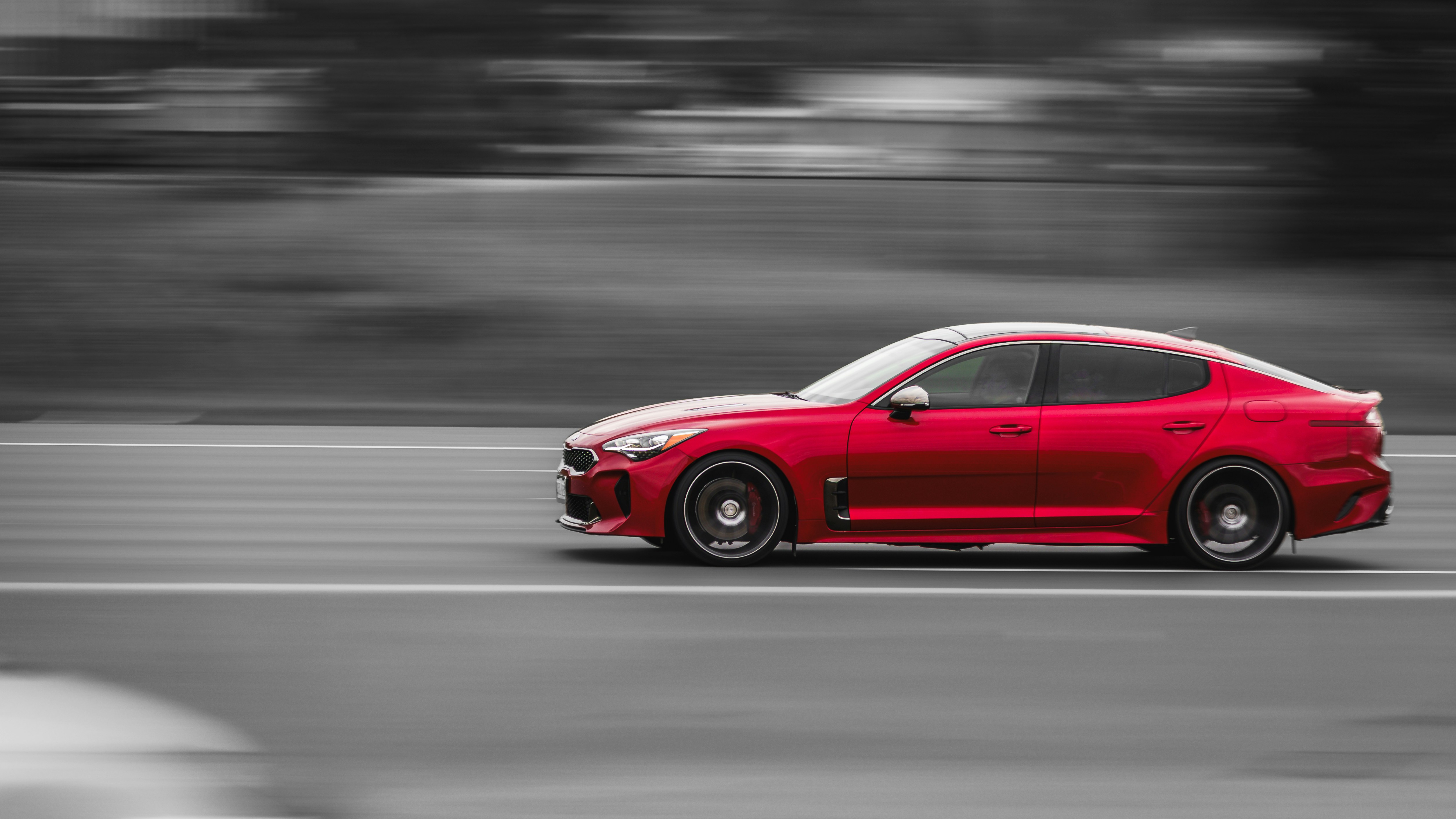 A red sports car speeds down a blurred road.