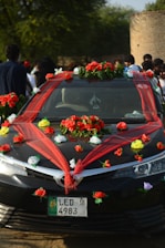Black car decorated with red and white flowers.