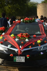 Black car decorated with red and white flowers.