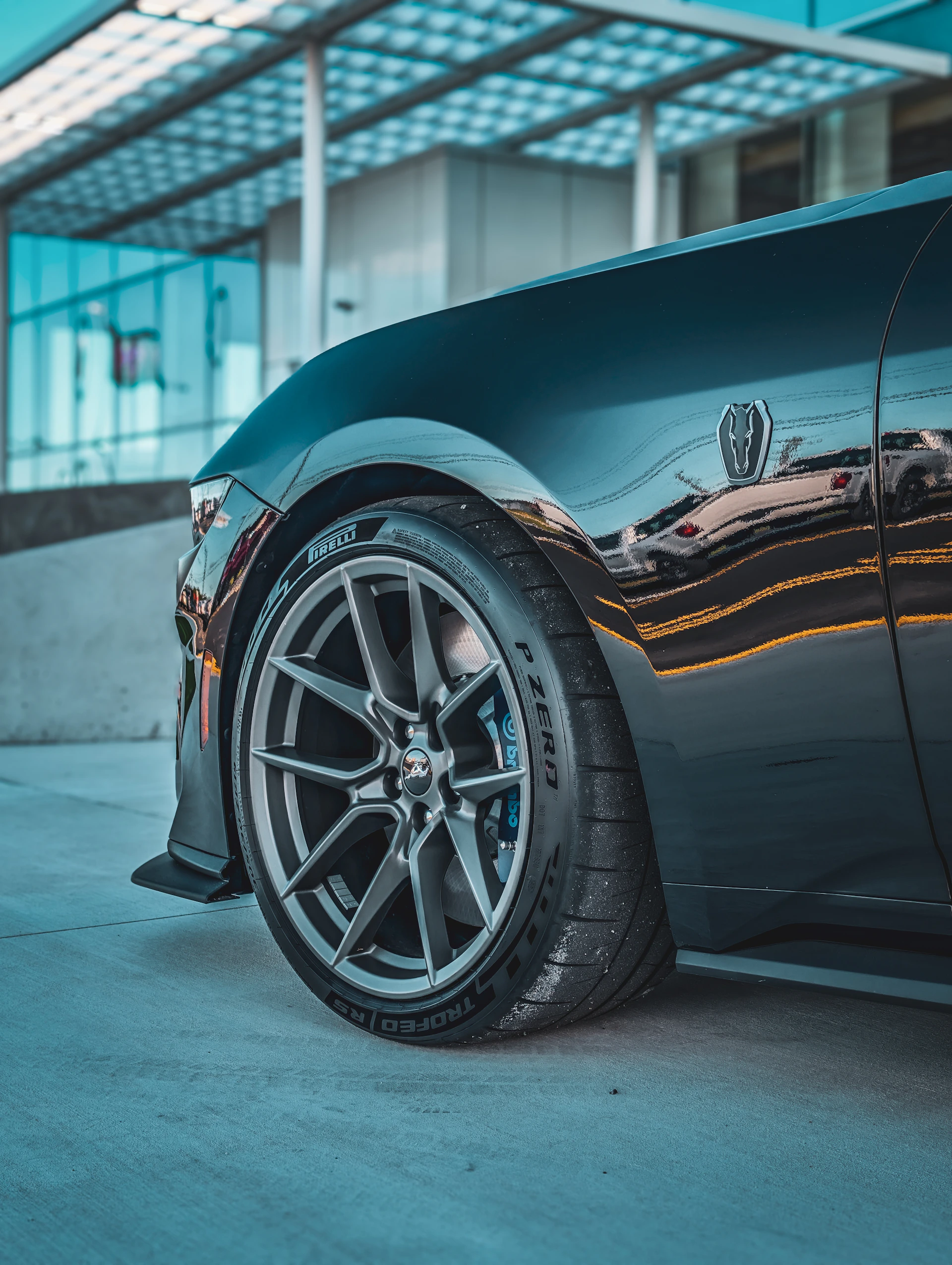 Close-up of a sleek, dark car wheel and fender.