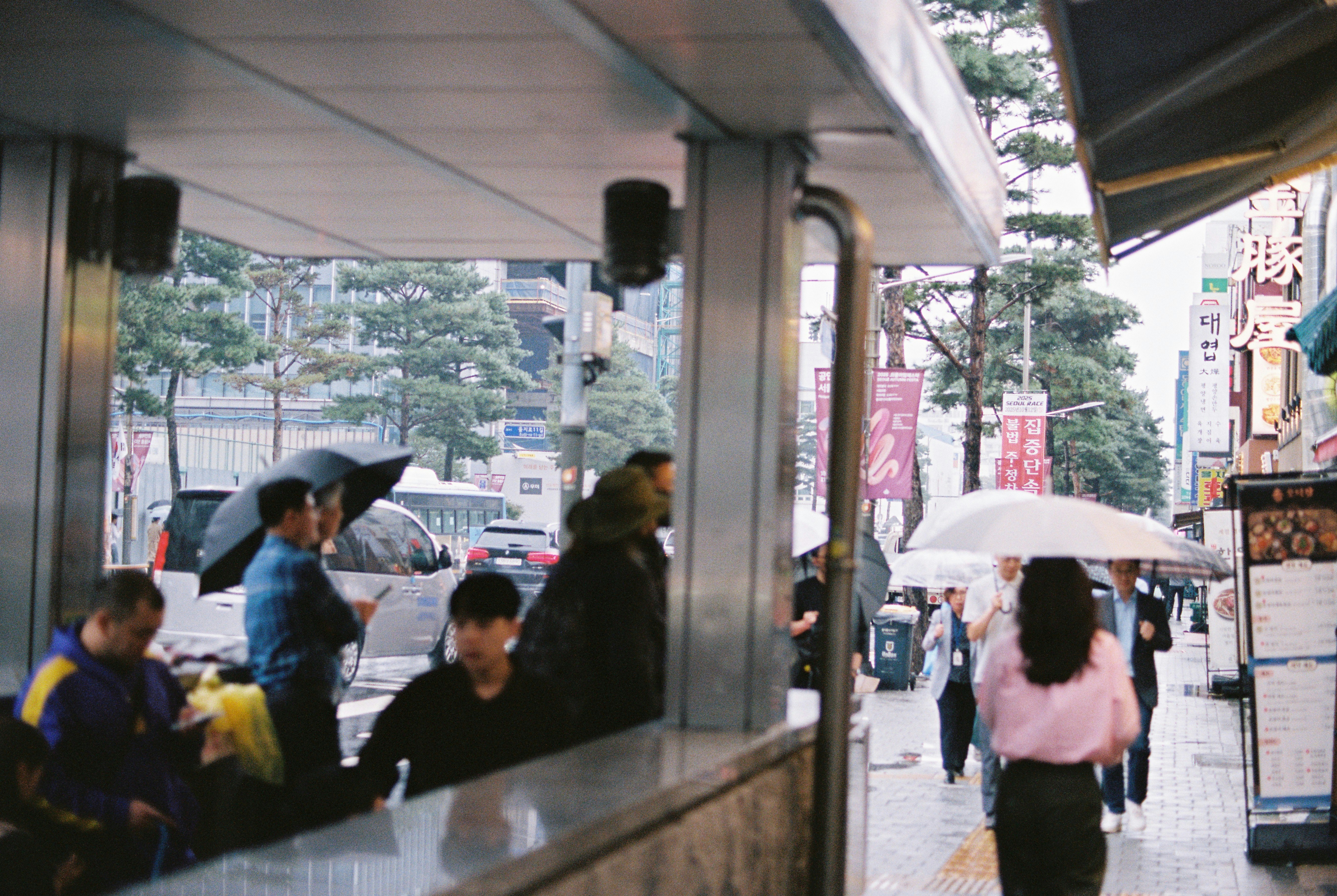 People with umbrellas walk on a wet city street.