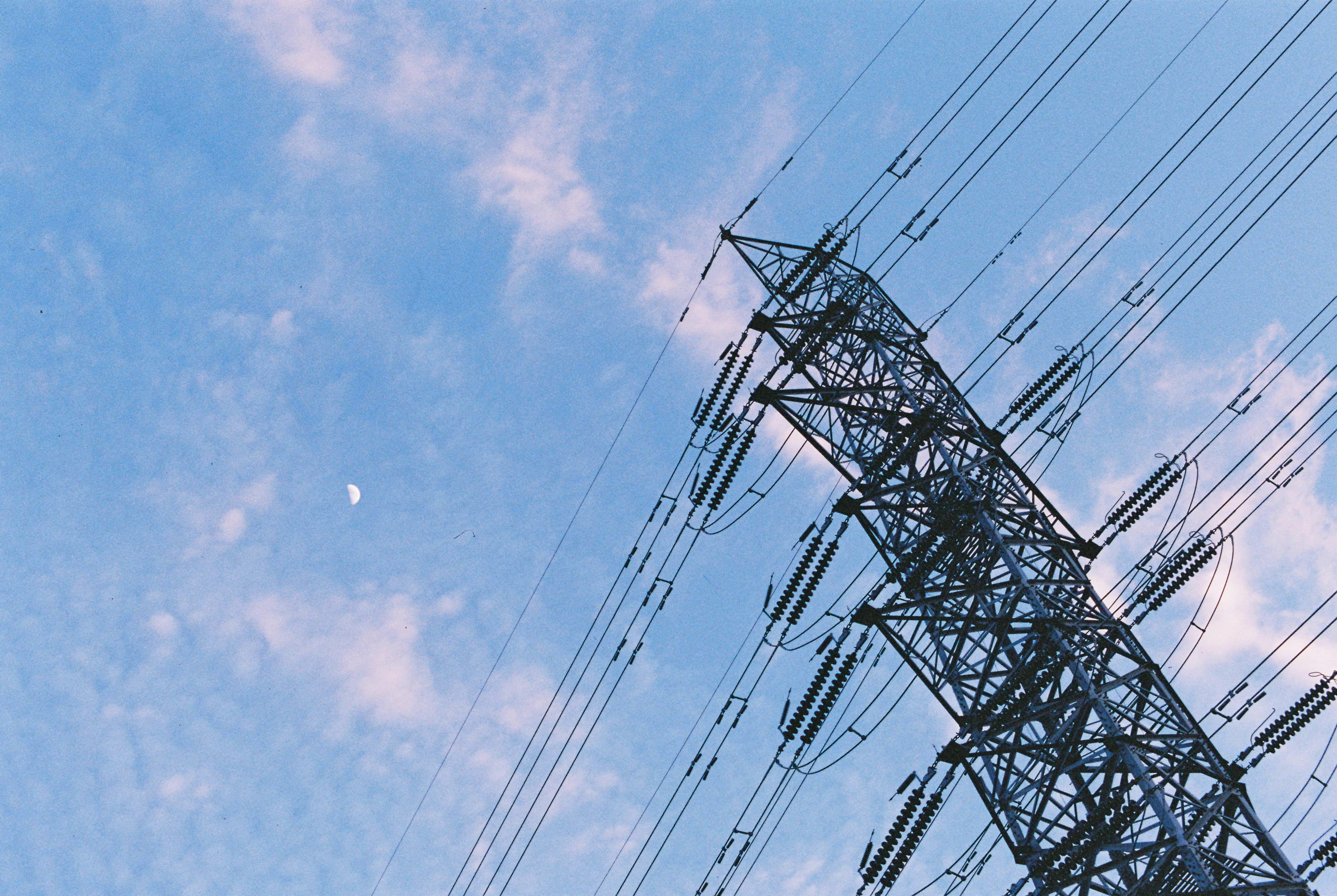 Power lines tower against a cloudy sky