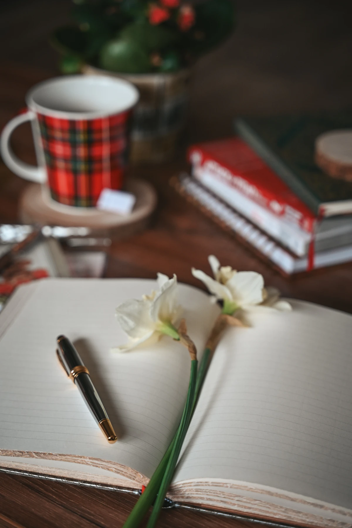 Open journal with white narcissus flowers and a warm mug in soft light